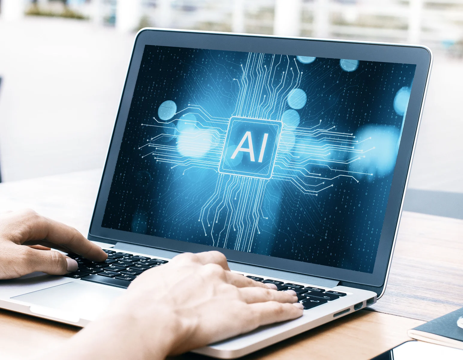 Hands on laptop with AI text on screen