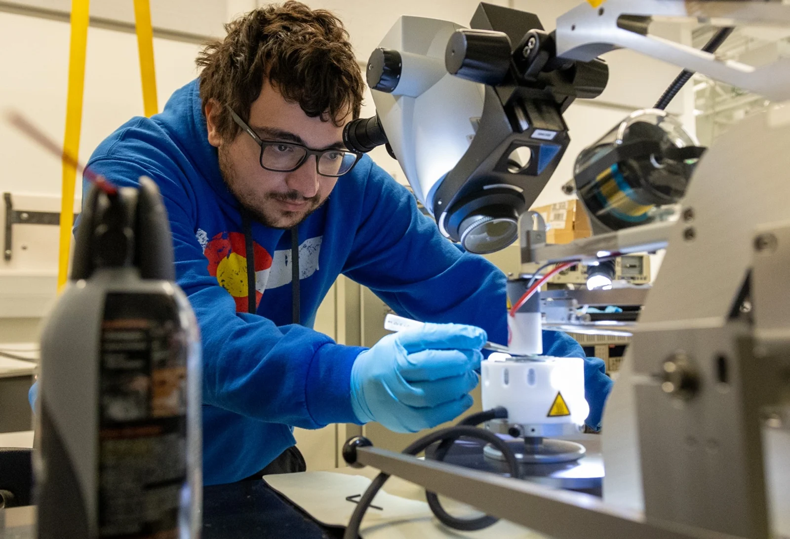 Quantum Engineering student working intently at a microscope in a laboratory setting.