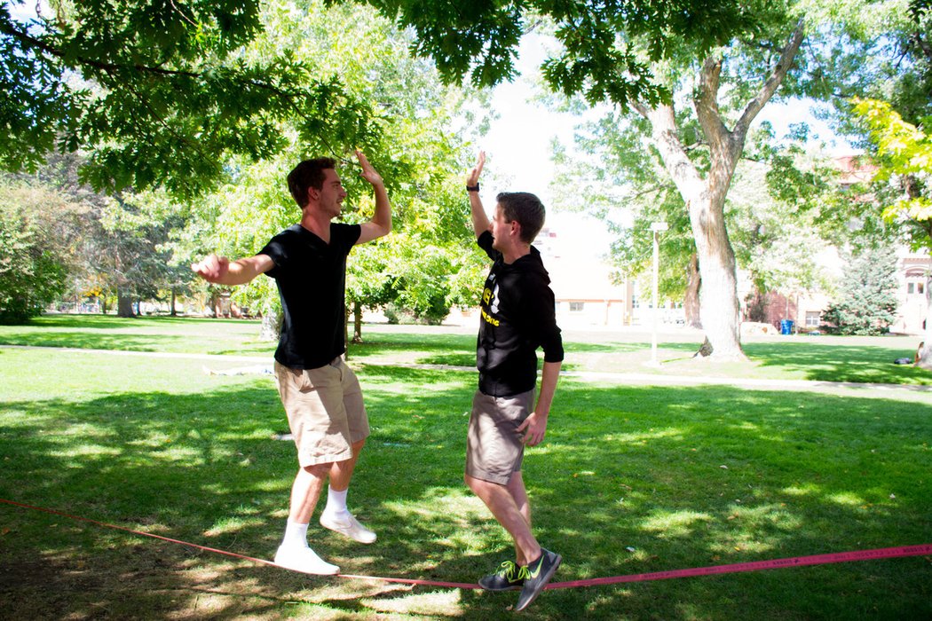 Mines students high-fiving on a slack line