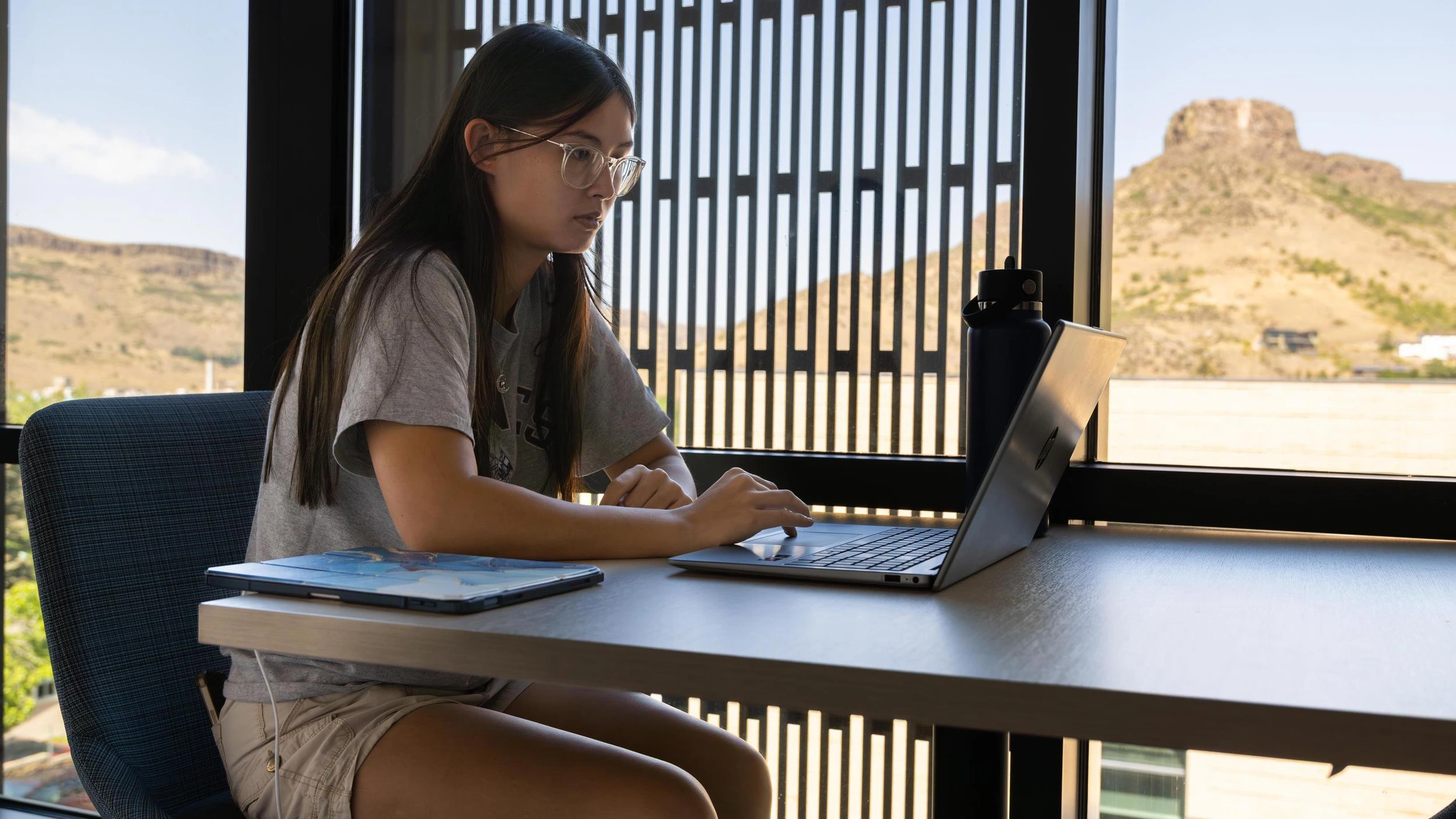 A Mines student sits at a table doing coursework on a laptop for the Information and System Science online certificate.