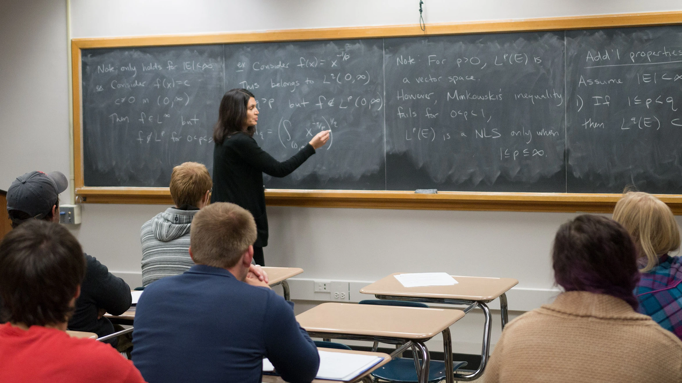 A woman standing in front of a blackboard in a classroom.