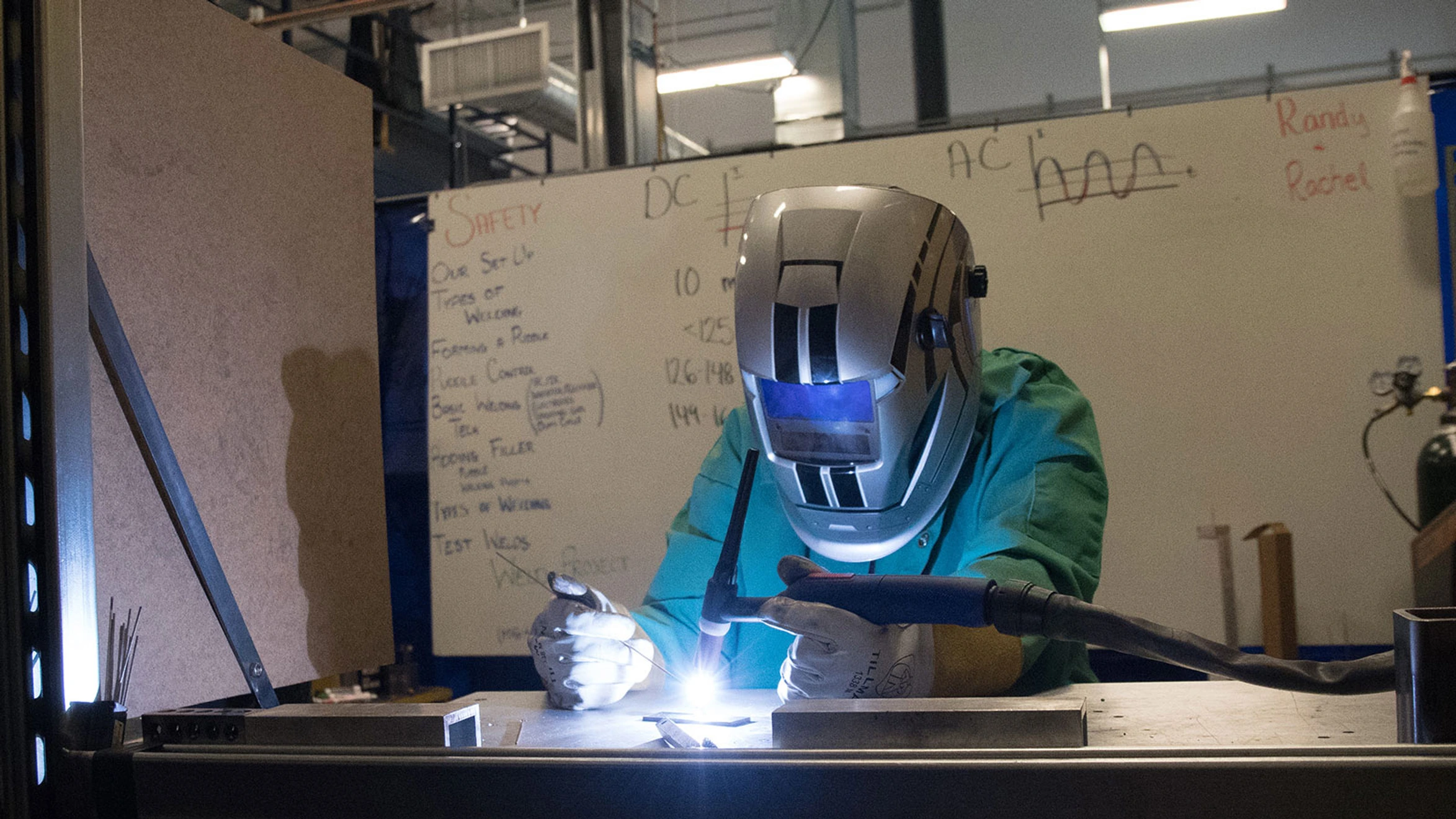 A welder working on a piece of metal in a workshop.