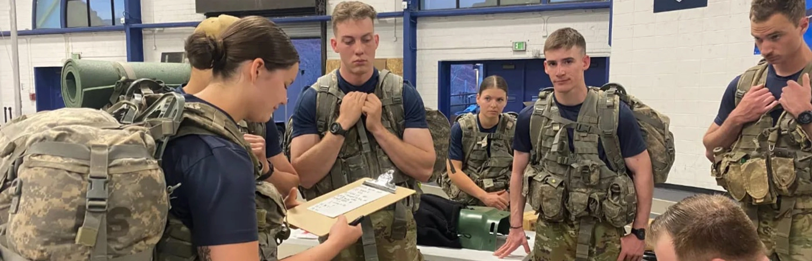 Mines Army ROTC cadets standing in a circle listening to the instructor with gear.