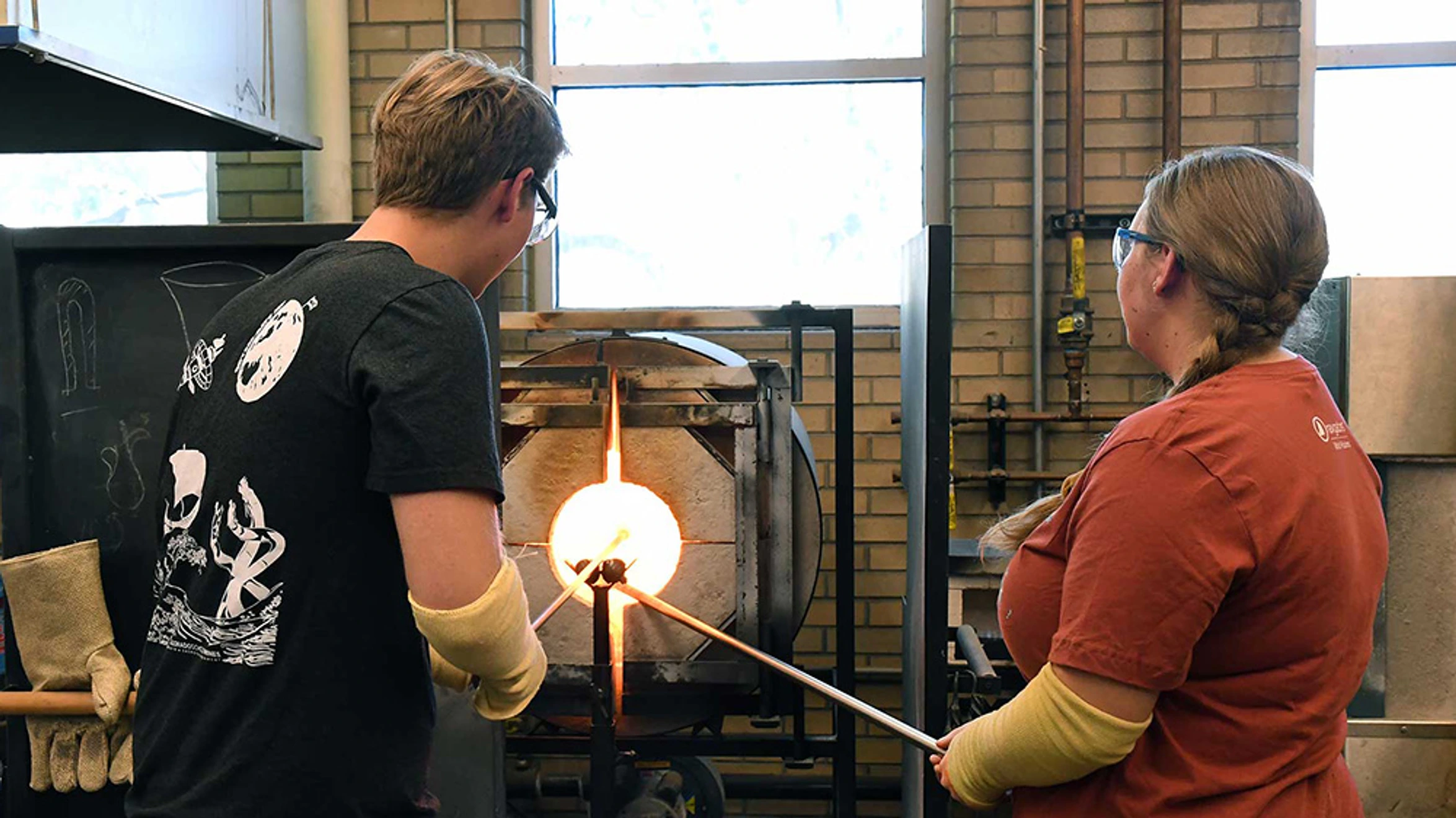 A man and a woman are working on a piece of glass.