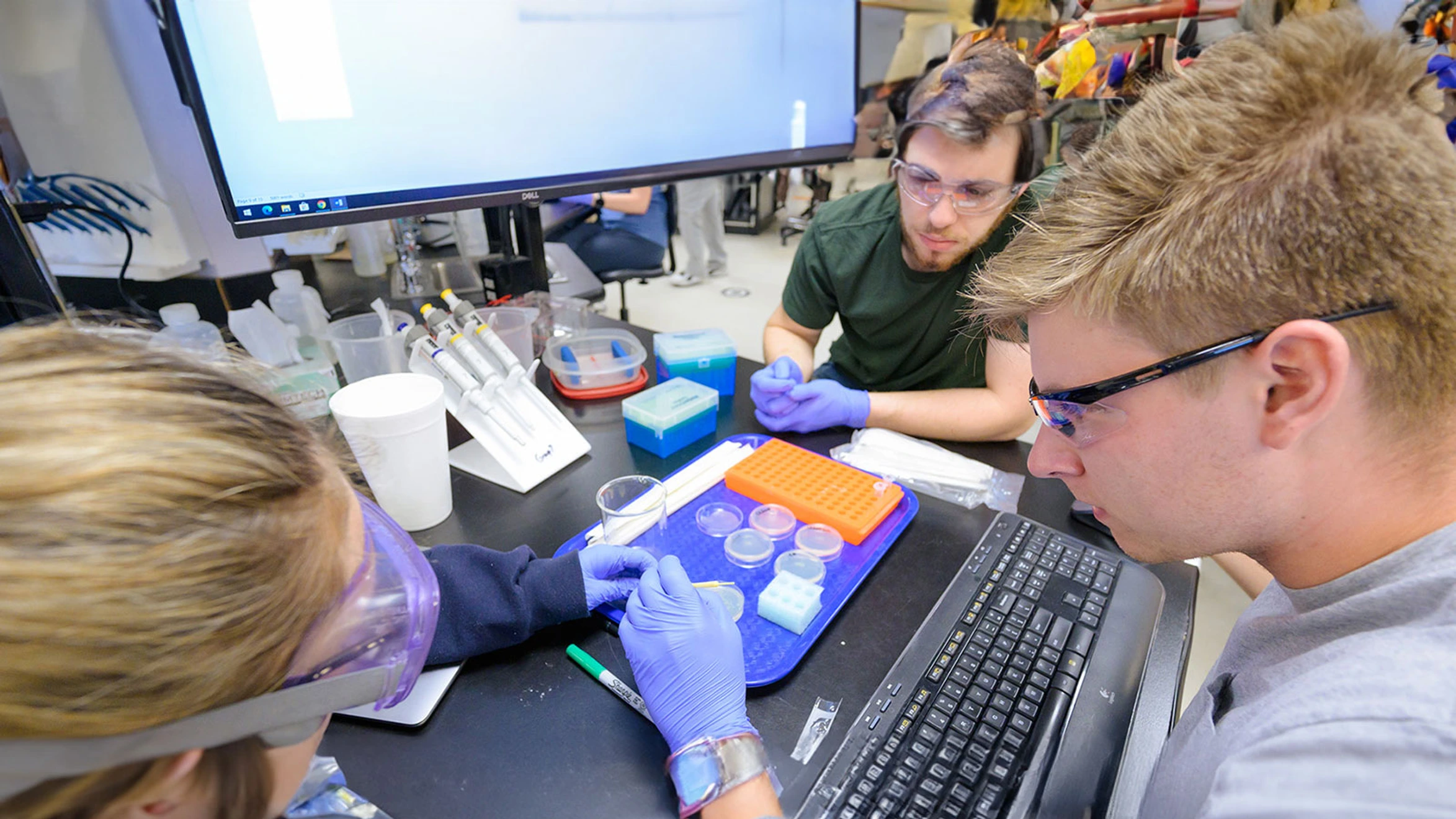 A group of people working in a lab with a computer.
