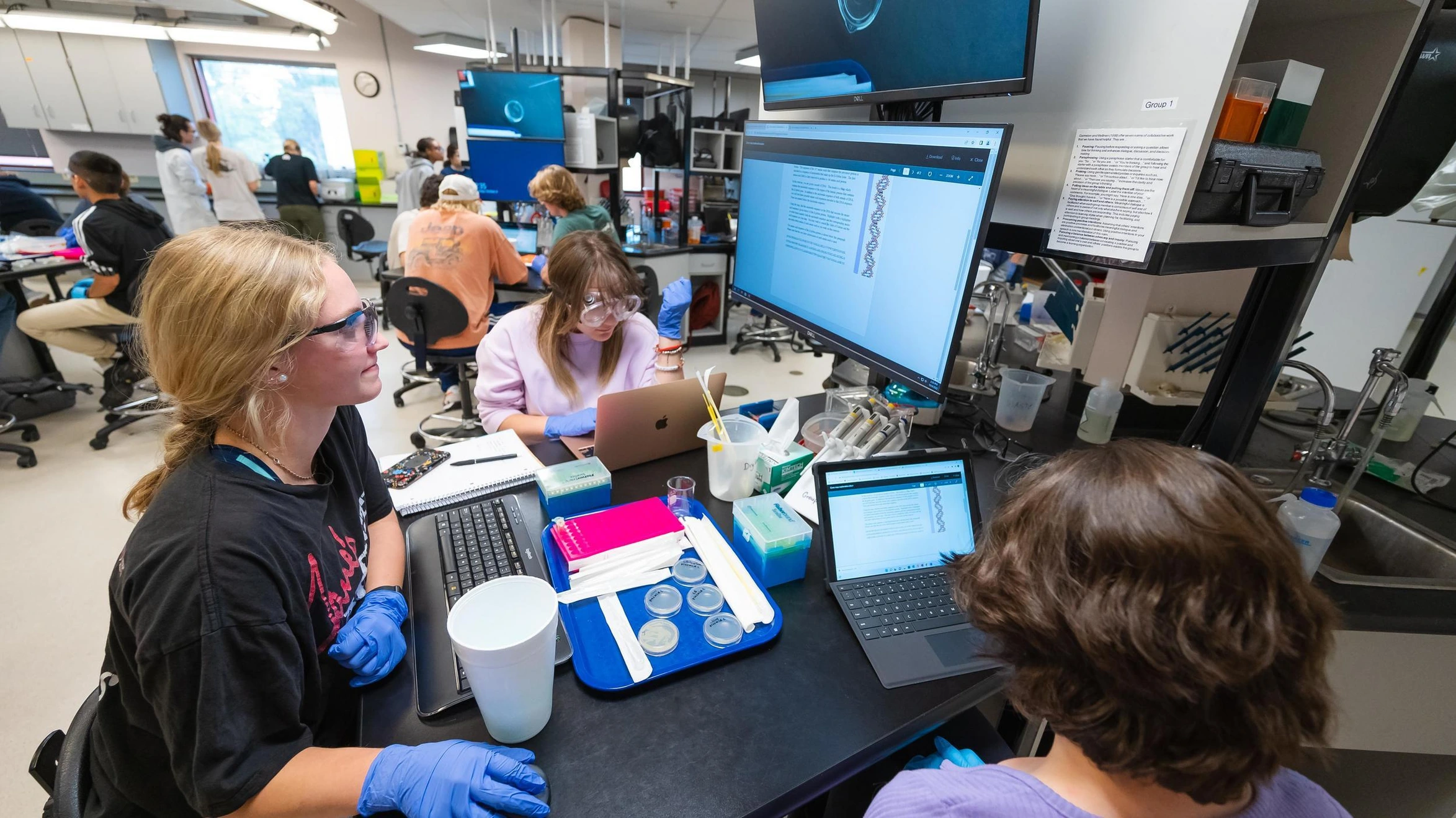 A group of people sitting around a table in a lab.