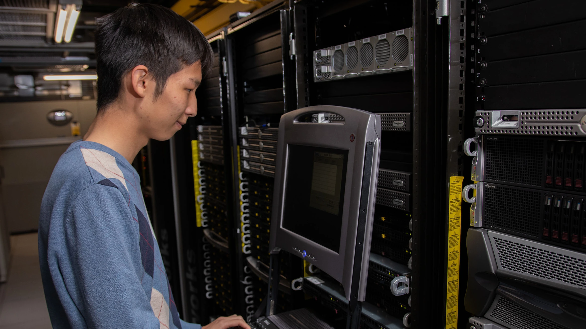 A man working on a computer in a server room.
