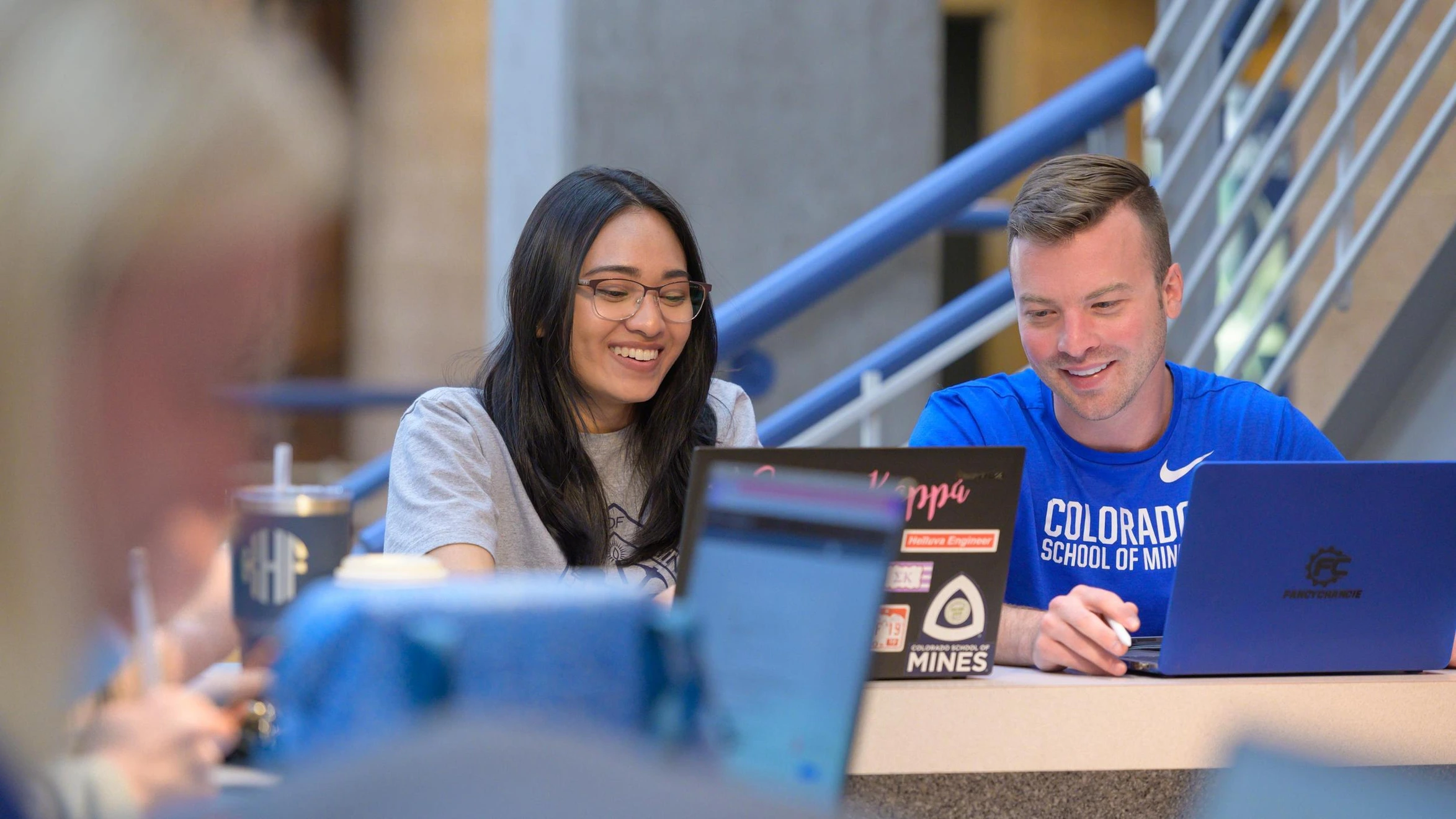 A man and a woman sitting at a table with laptops.