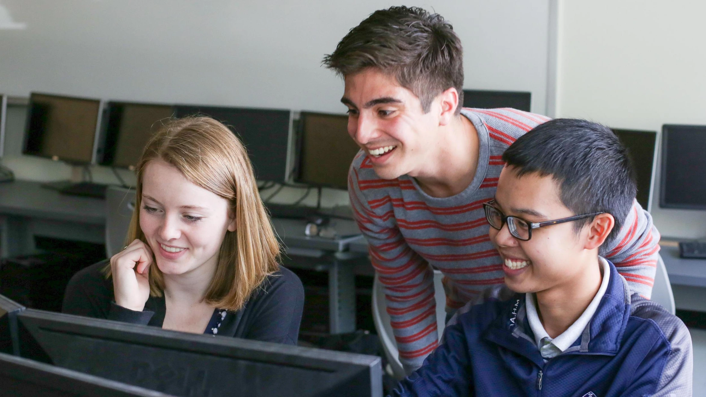 A group of young people looking at a computer screen.