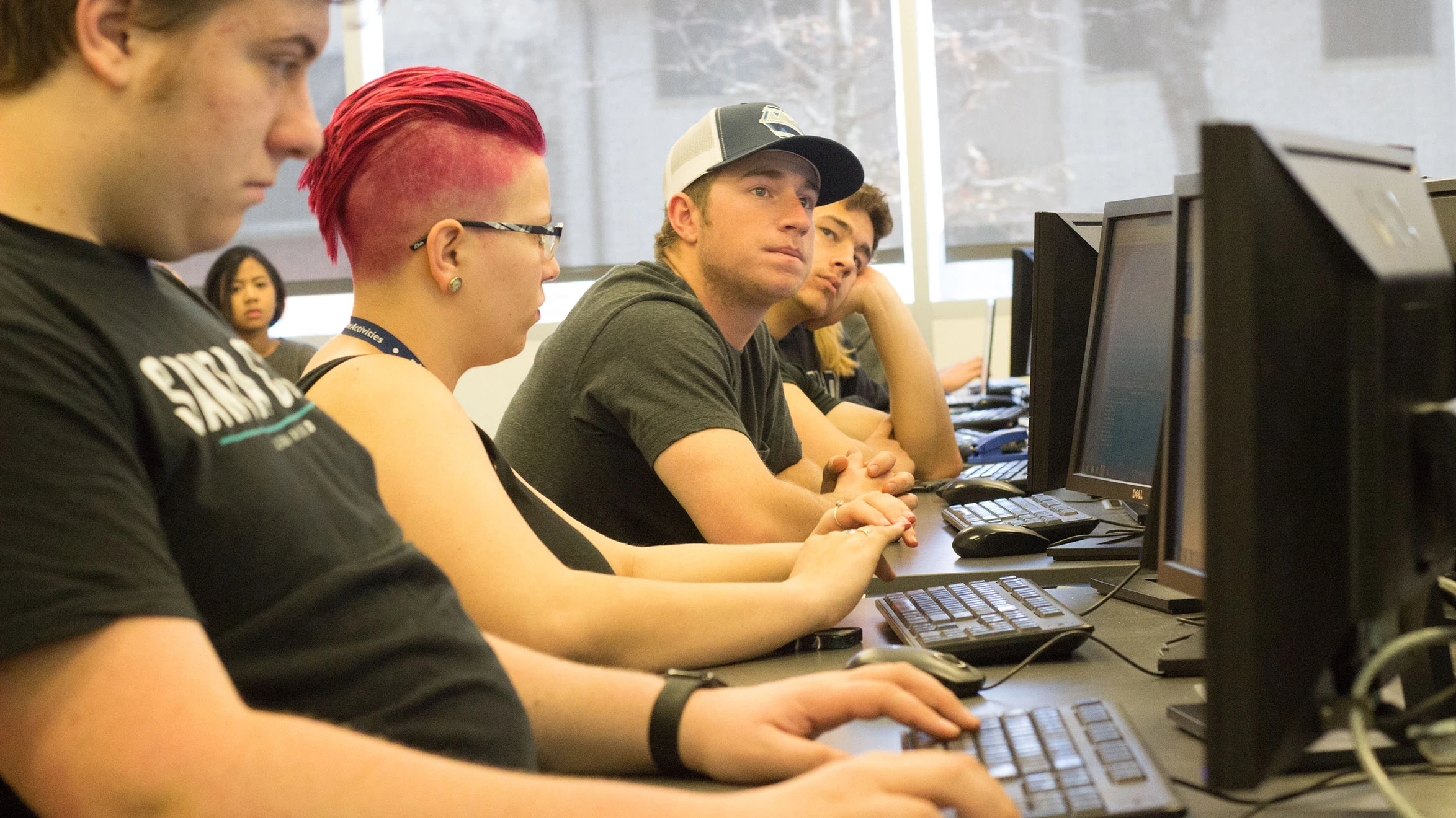 A group of young people sitting at computers in a computer lab.