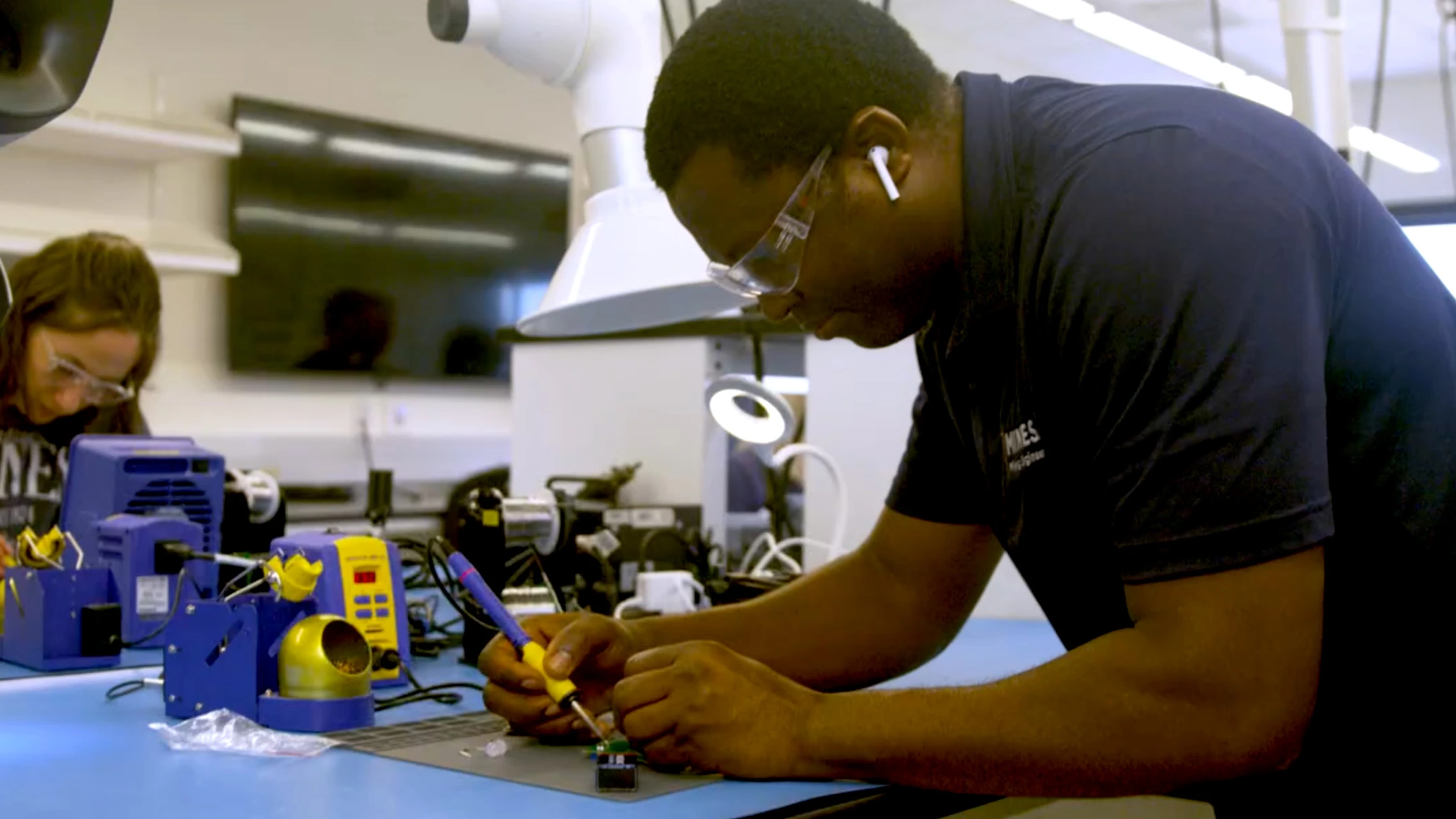 A man and a woman working on electronics in a lab.