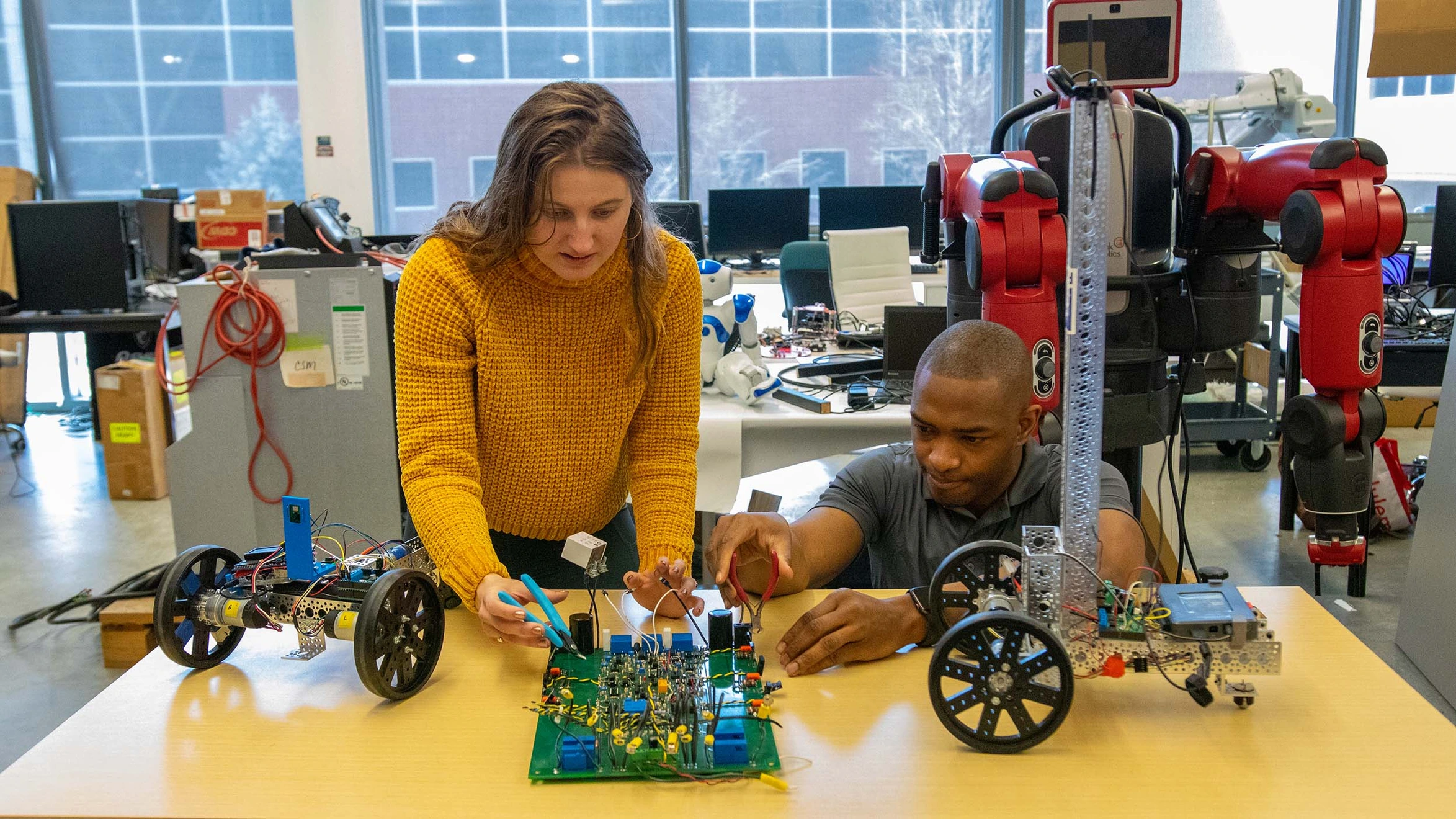 A man and a woman working on a robot in a lab.