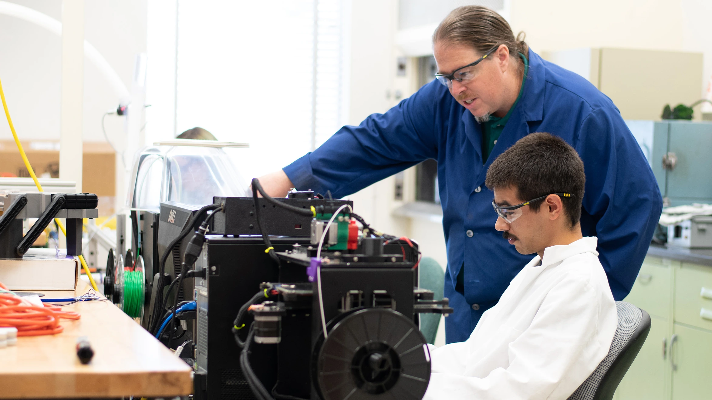 A man and a boy working on a machine in a lab.