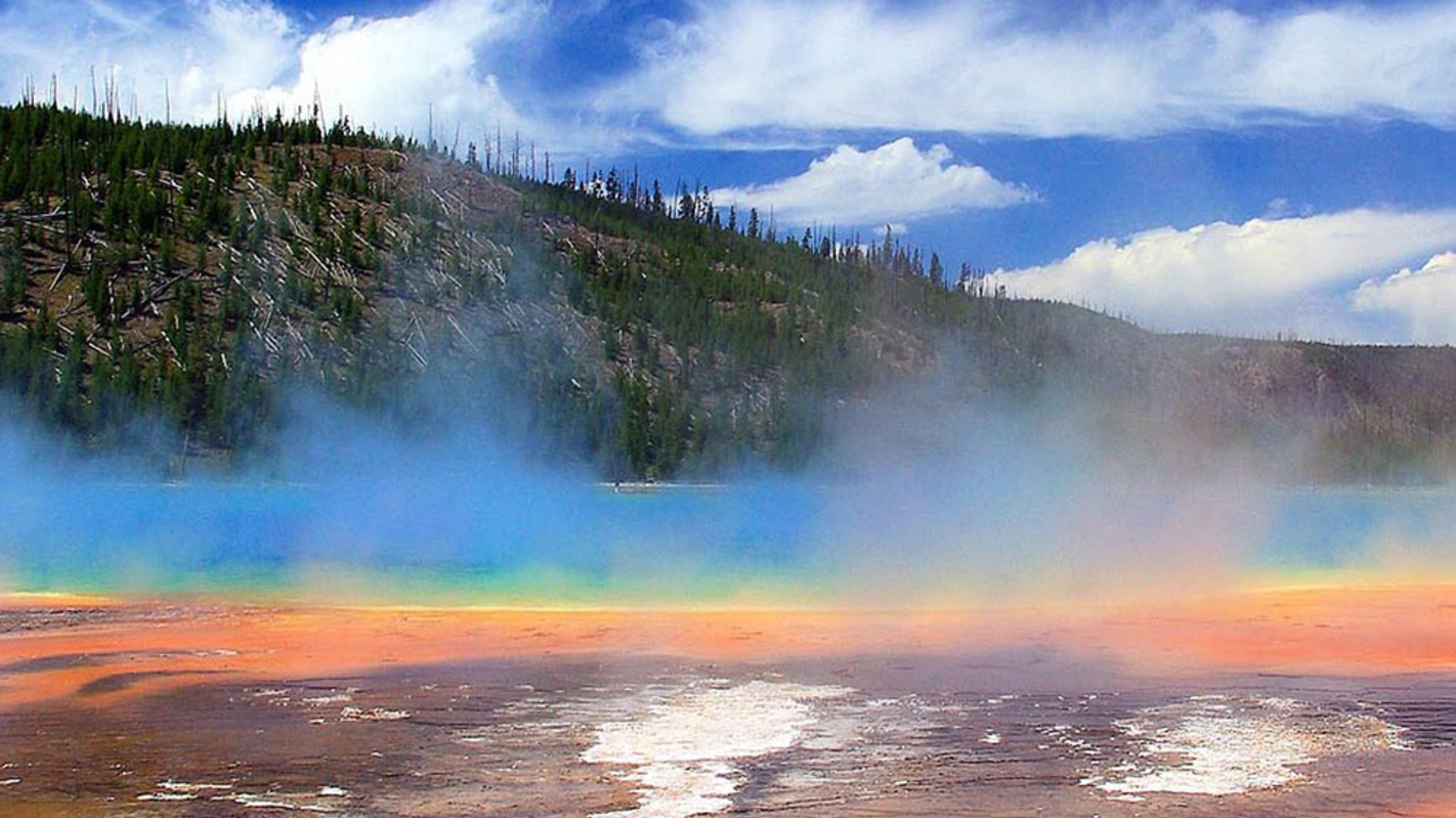 A rainbow in the sky over a body of water.