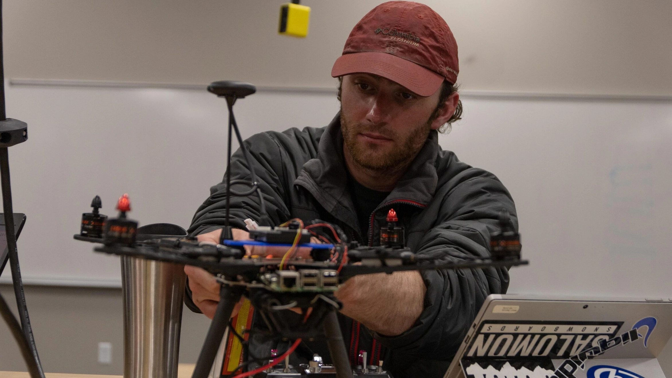 A man in a red hat is working on a drone.