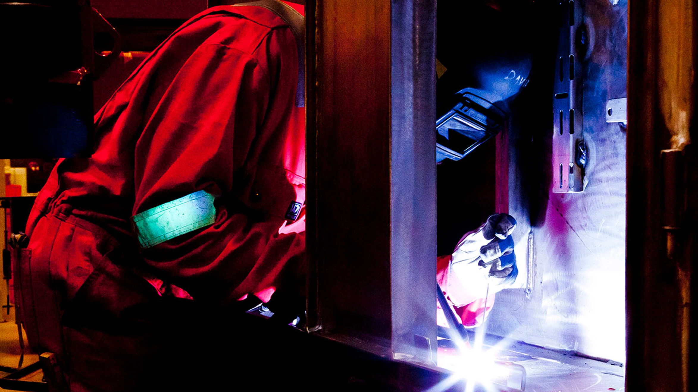A welder working on a piece of metal in a workshop.