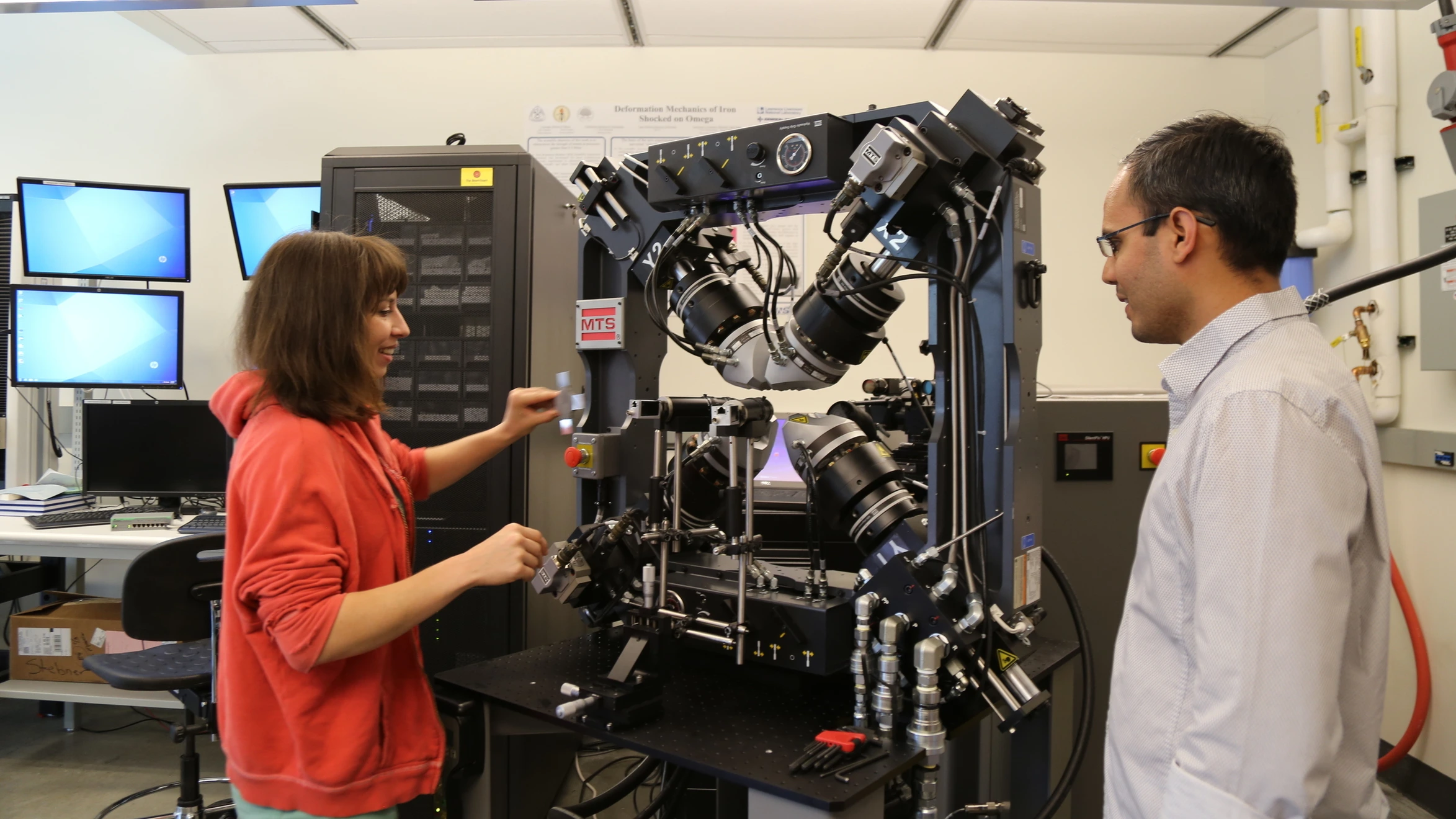 A man and a woman looking at a machine in a lab.