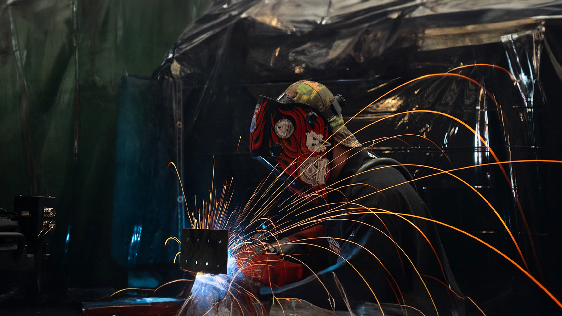 A welder working on a piece of metal with sparks.