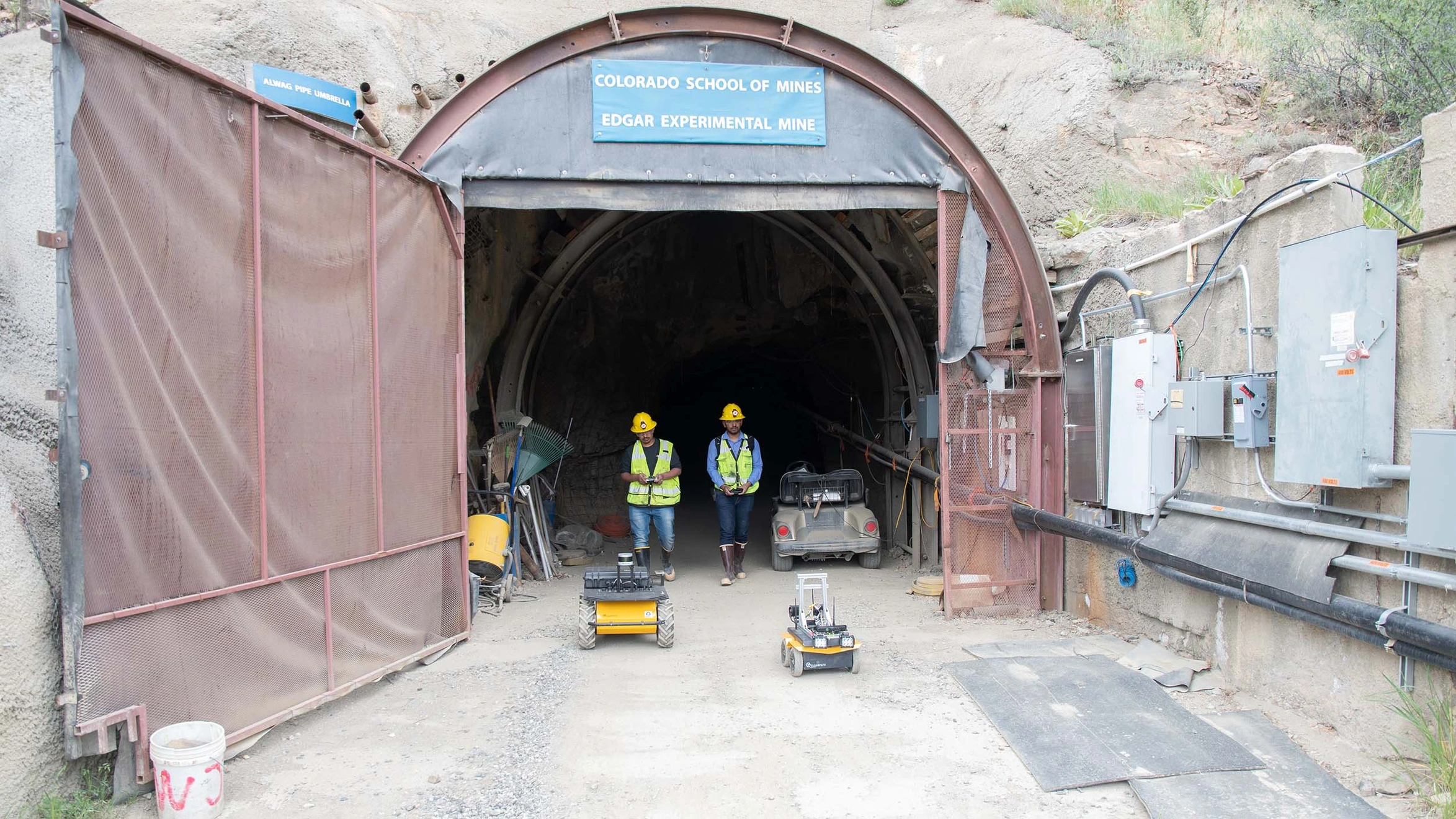 A group of men standing in front of a tunnel.