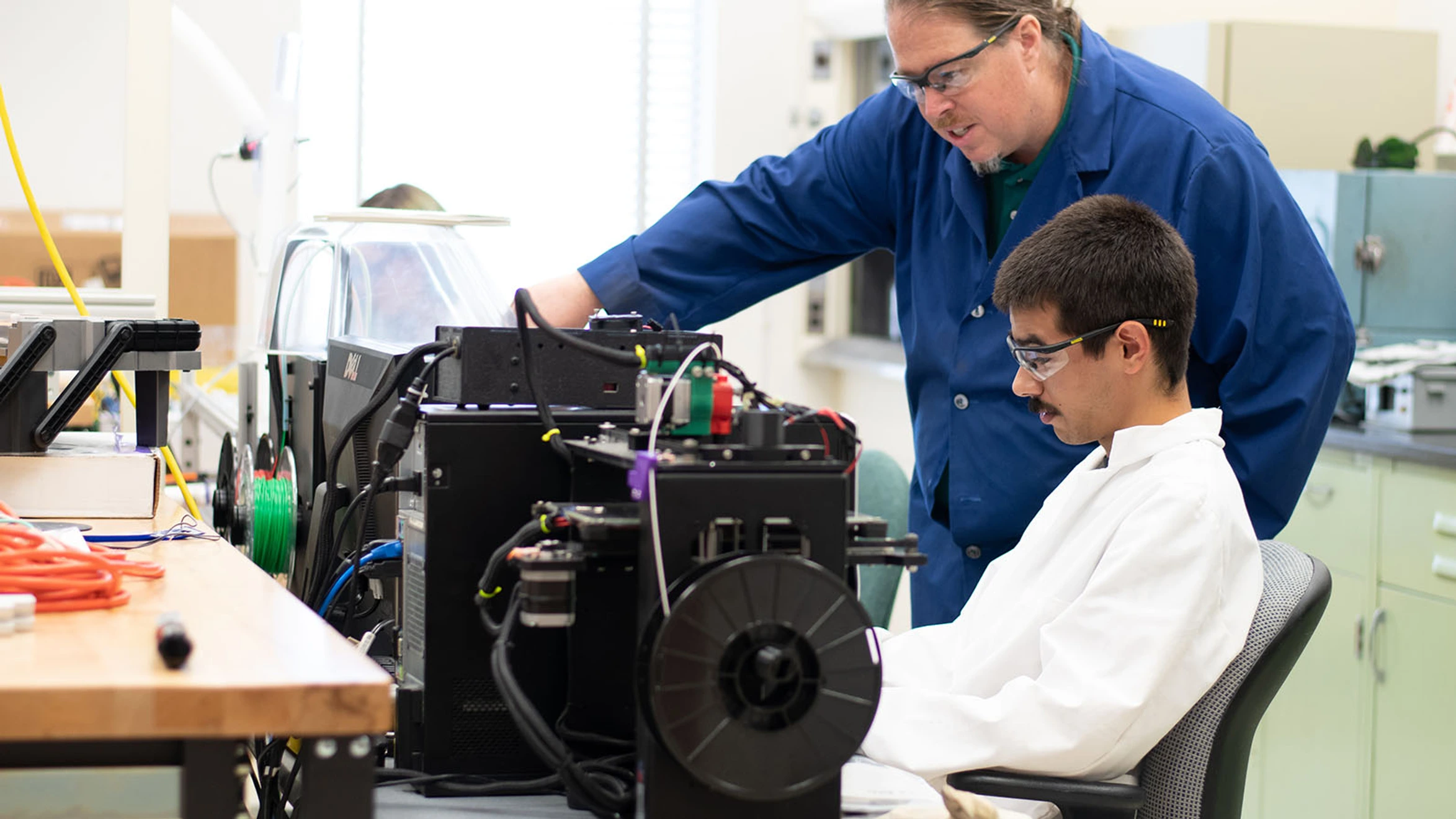 Two men working on a machine in a lab.