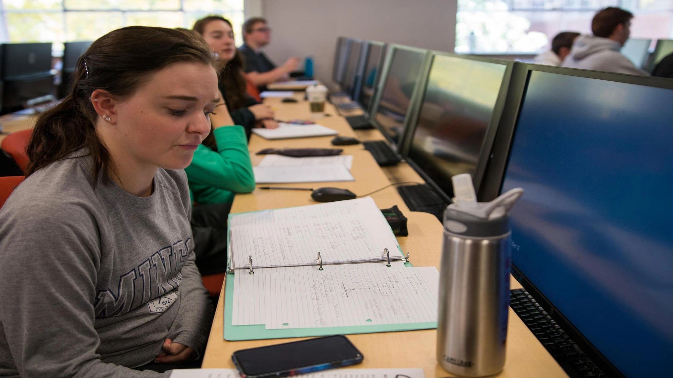 A group of people sitting at a desk in front of computers.