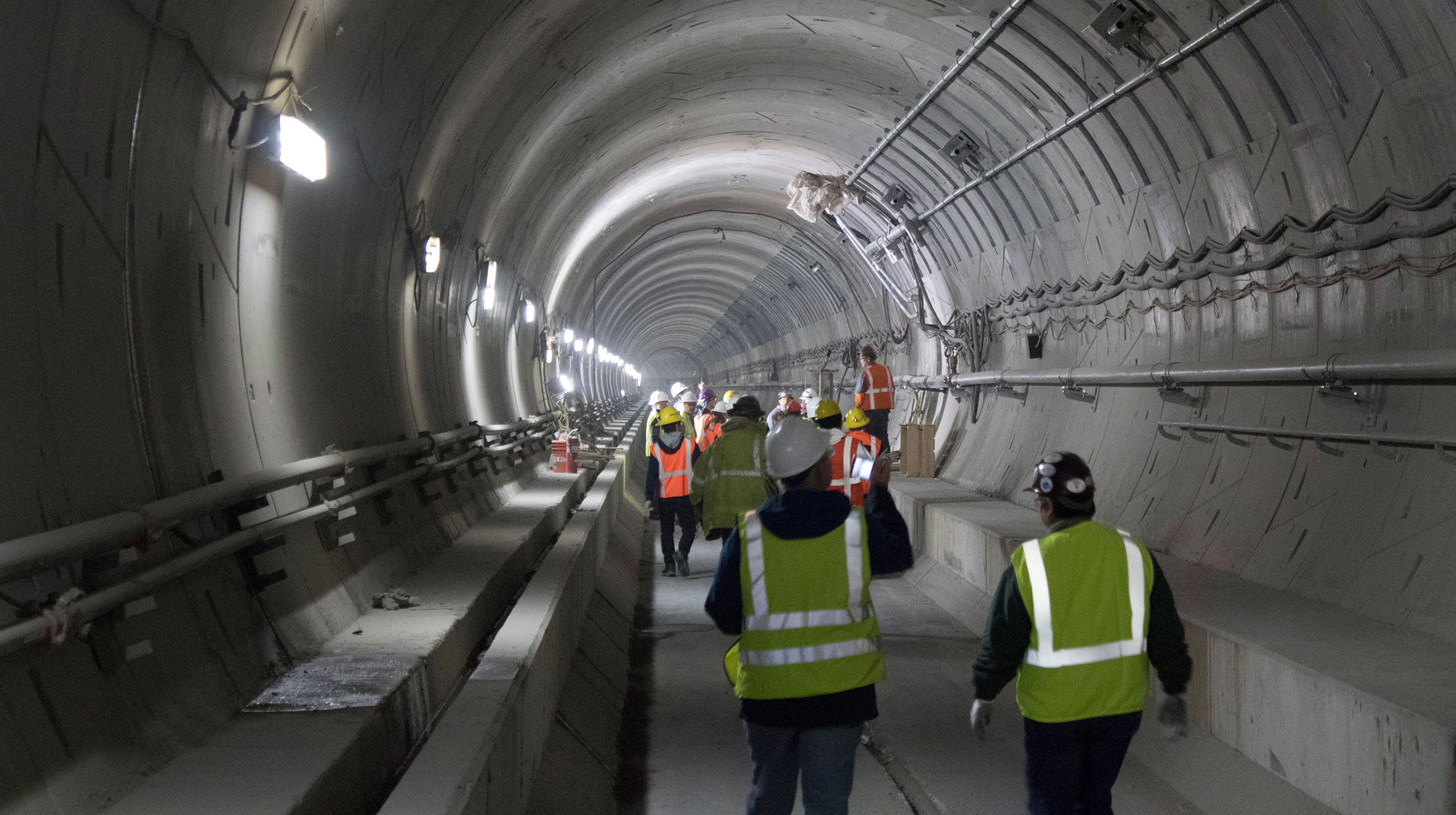 A group of construction workers walking through a tunnel.