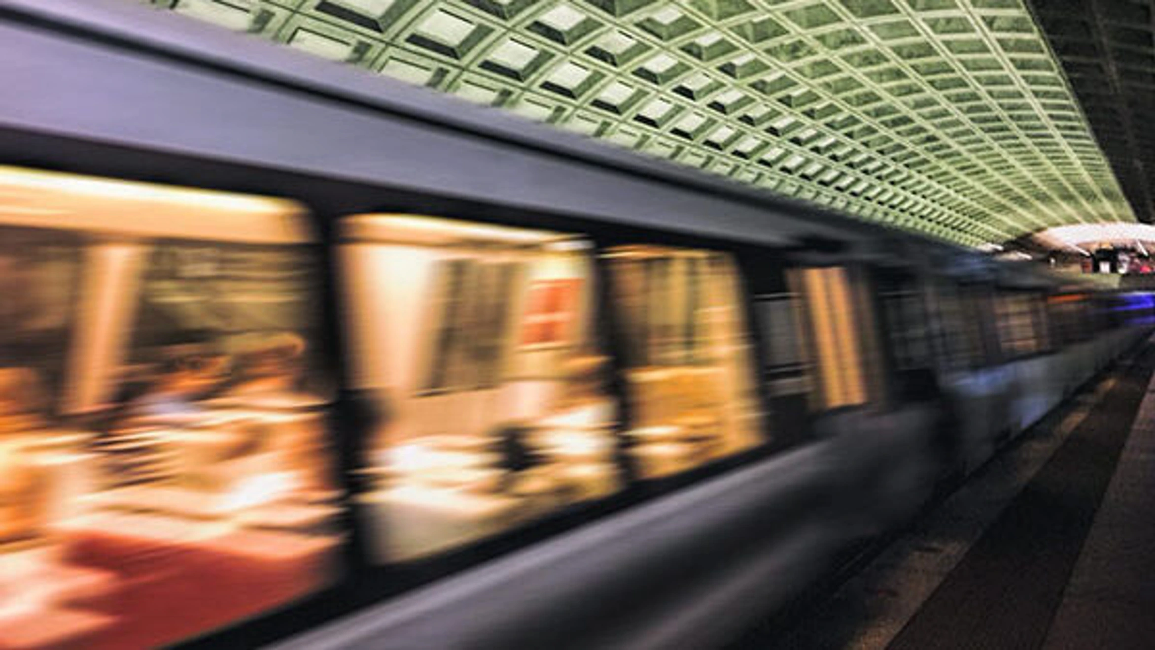 A subway train traveling through a subway station at night.