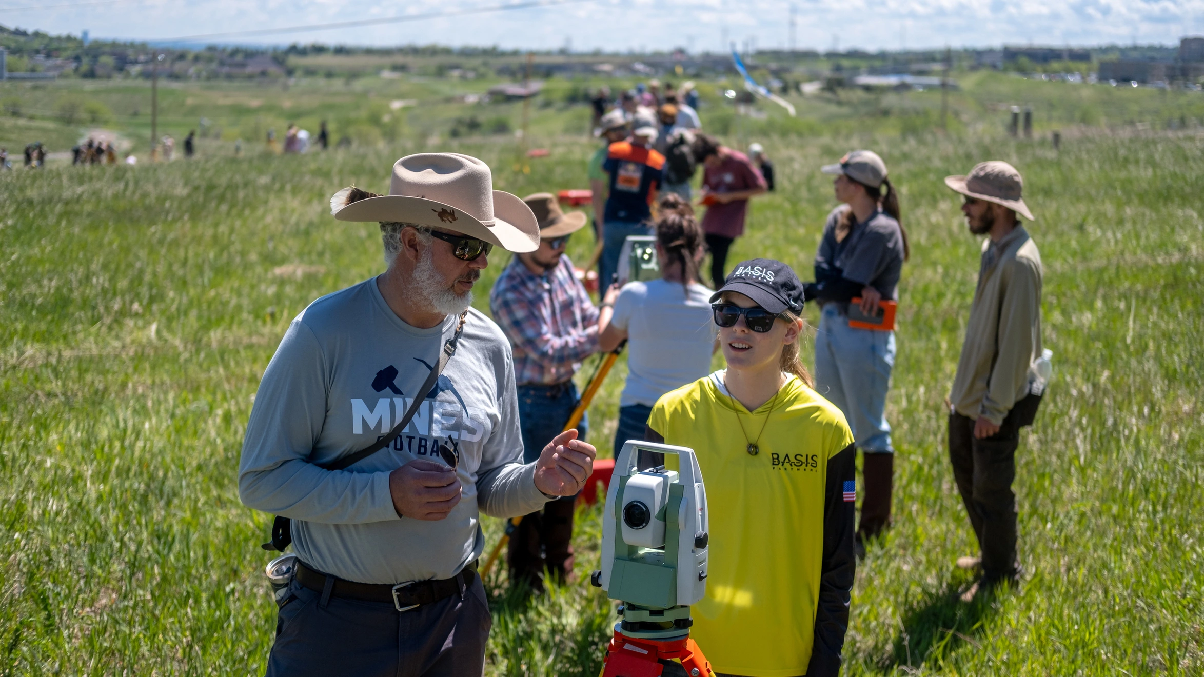 A Mines professor and Civil and Environmental Engineering student stand in a field using survey equipment.