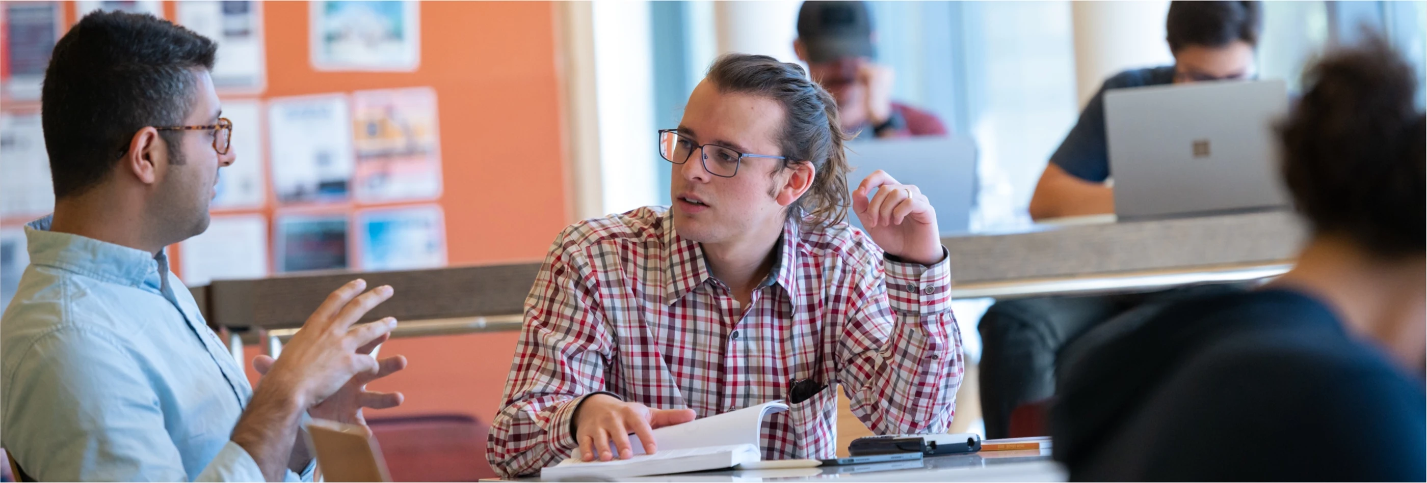 Two graduate students sitting a table going over course materials.