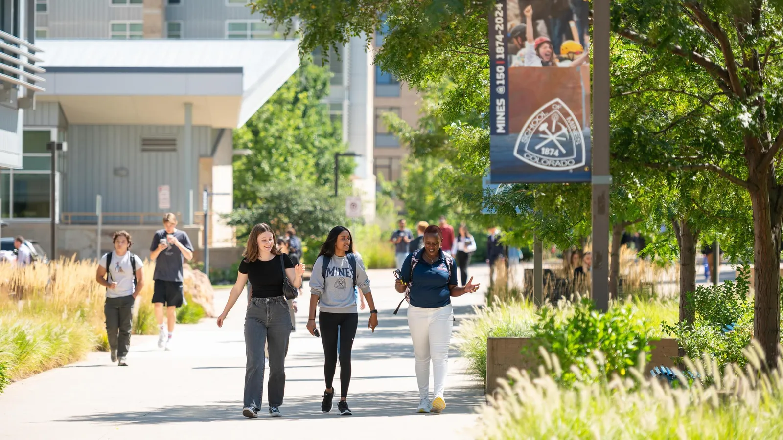 Colorado School of Mines students walk along a path on campus on a sunny afternoon.