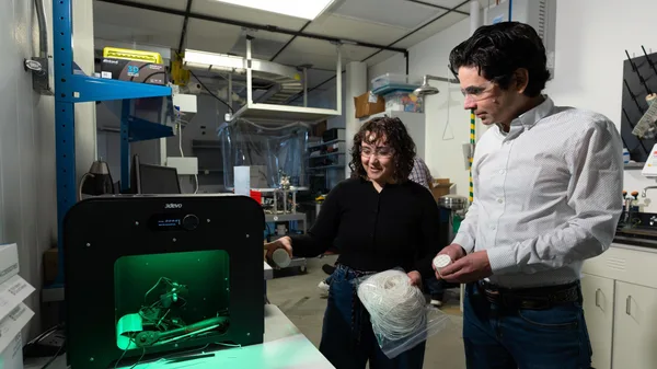 An Advanced Energy Systems master's student explains the inner workings of lab equipment to a colleague.