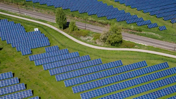 A field of solar panels on the side of a road.