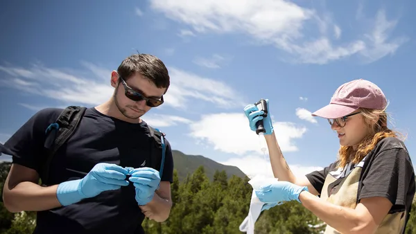 A man and a woman wearing blue gloves and a pink hat.