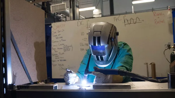 A welder working on a piece of metal in a workshop.
