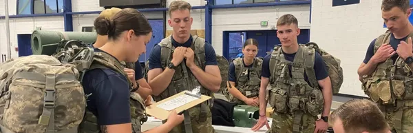 Mines Army ROTC cadets standing in a circle listening to the instructor with gear.