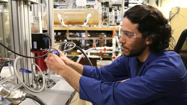 A man in a blue shirt is working on a machine.