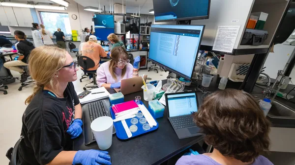 A group of people sitting around a table in a lab.