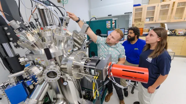A group of people standing around a machine in a lab.