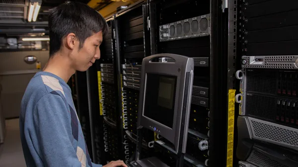 A man working on a computer in a server room.