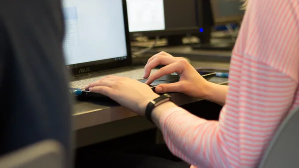 A woman sitting at a desk using a laptop computer.