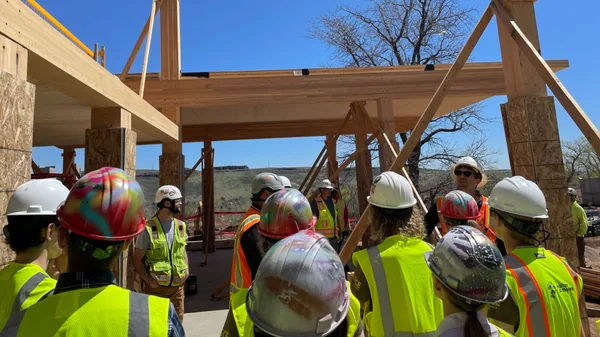 A group of construction workers standing around a building under construction.