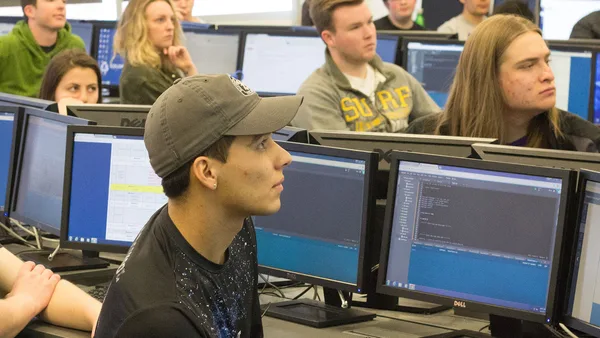 A group of people sitting at computers in a computer lab.
