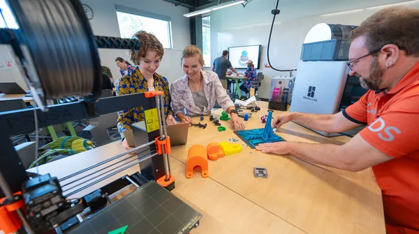 A group of people working on a 3D printer.