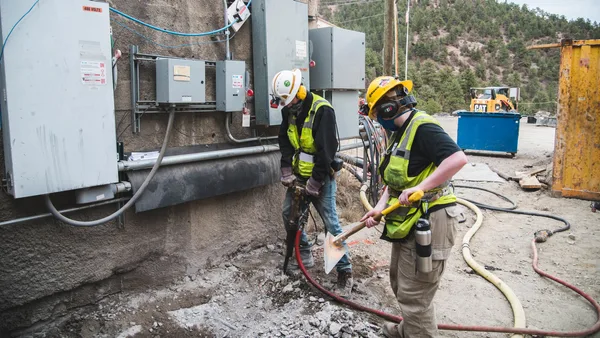 A group of men in hard hats and safety vests working on a construction site.