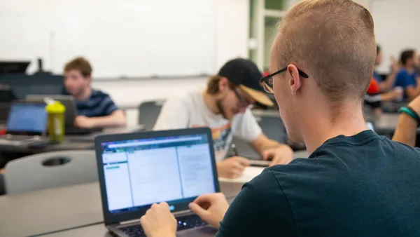 A group of people sitting around a table working on laptops.