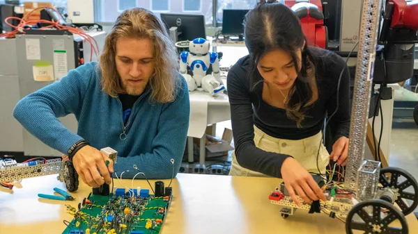 A man and a woman working on a robot.