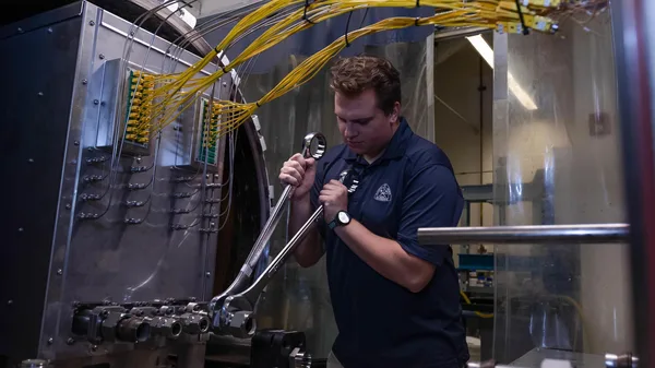 A man in a blue shirt is working on a machine.