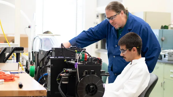 A man and a boy working on a machine in a lab.