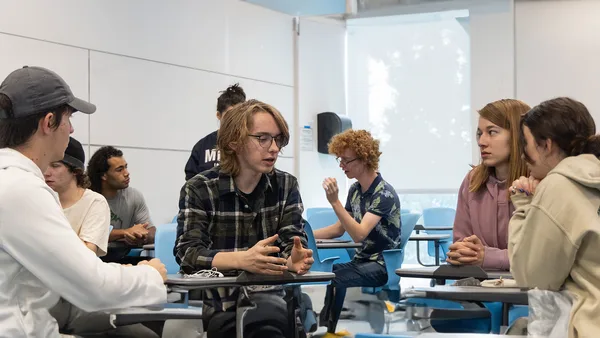 A group of people sitting around a table in a classroom.