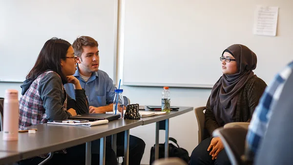 A group of people sitting around a table in a classroom.